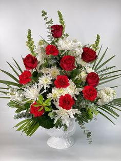 a white vase filled with red and white flowers