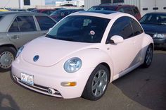 a pink car parked in a parking lot next to other cars