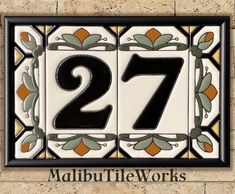 the number twenty seven is painted on a wall with an ornate border and black frame