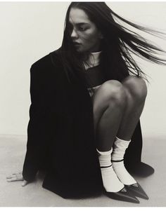 a woman with long hair sitting on the ground