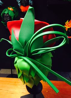 a close up of a vase on a table with paper flowers in the back ground