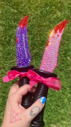 someone is holding two small candles with pink bows on them in their hand, and the other one has purple beads