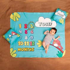 a baby laying on top of a blue blanket with numbers and birds in it's center