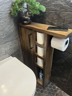 a bathroom with a toilet and some rolls of toilet paper on the shelf next to it