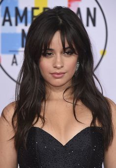 a close up of a person wearing a black dress with long hair and diamond earrings