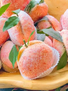 some sugar covered strawberries are on a wooden platter with green leaves and sprinkles