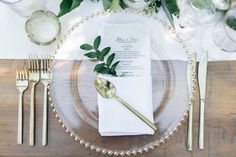 a place setting with silverware and greenery