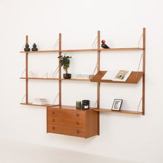 a wooden shelf with books and vases on it next to a wall mounted shelving unit