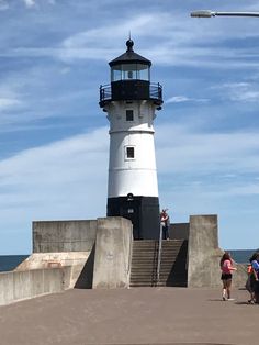 people are walking towards the lighthouse on a sunny day