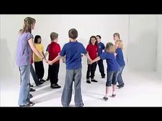 a group of people standing around each other in front of a white wall with their hands together