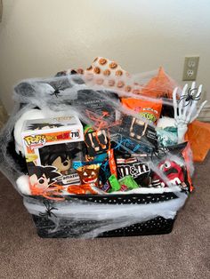 a basket filled with halloween items on top of a carpeted floor next to a wall