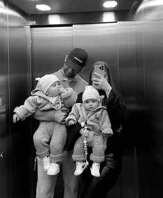 a man taking a selfie with two small children in front of an elevator door