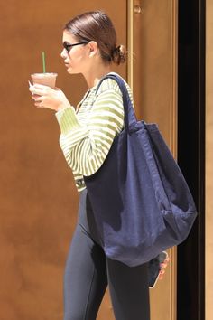 a woman in leggings is holding a drink