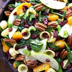 a salad with apples, cranberries and nuts in a bowl on a table