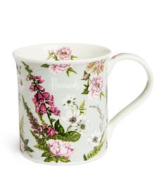 a white coffee cup with pink flowers on the outside and green leaves on the inside