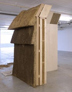 a building made out of straw and wood in an empty room with no people around