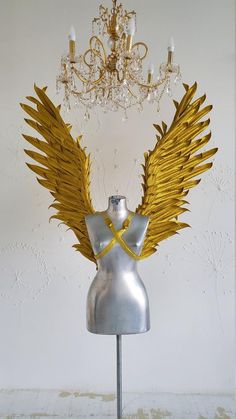 a silver mannequin with gold wings and a chandelier