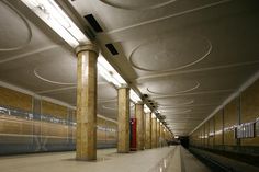 an empty subway station with columns and lights