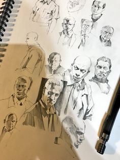 a notebook with some drawings of men and women in suits on top of it next to a pen