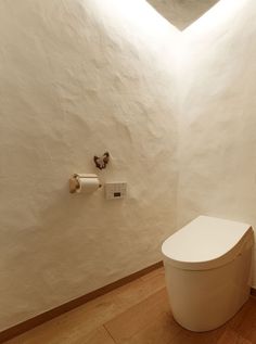 a white toilet sitting in a bathroom next to a roll of toilet paper on the wall