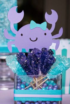 there is a purple crab on top of some blue candies in a glass vase