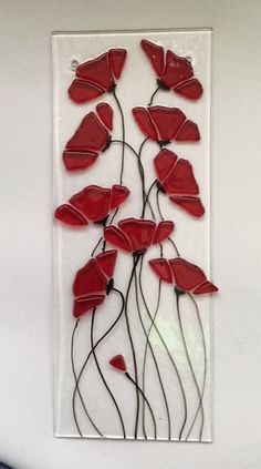 a glass panel with red flowers in the shape of leaves on it's side