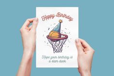 two hands holding up a birthday card with a basketball hoop and a party hat on it