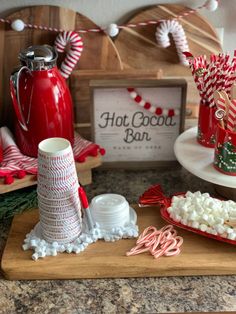 some candy canes and marshmallows are on a cutting board next to the hot cocoa bar sign