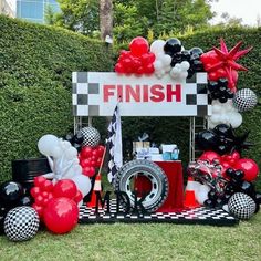 the finish sign is decorated with red, black and white balloons in front of it