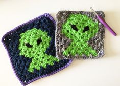 two crocheted squares with green faces on them, one is blue and the other is gray