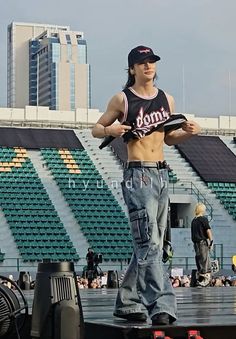 a man standing on top of a stage with his hands in his pockets and holding a skateboard