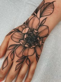 a woman's hand with a flower tattoo on it