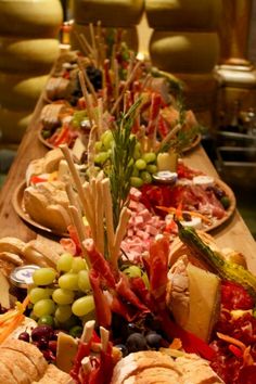 a long wooden table topped with lots of different types of sandwiches and fruit on top of it