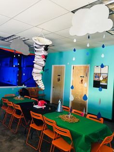 an empty room with green table cloths and orange chairs in front of blue walls