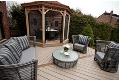 an outdoor living area with chairs, table and grill