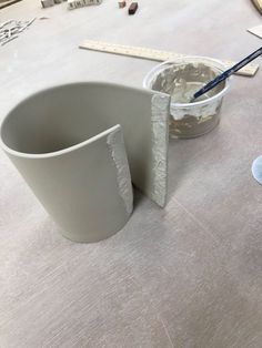 a cup is sitting on the table next to some construction materials and a paintbrush