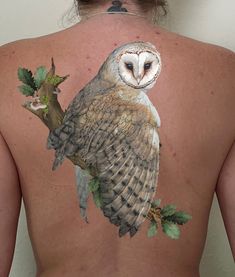 an owl painted on the back of a woman's upper body, with leaves around it