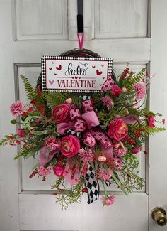 a valentine's day wreath with pink flowers and greenery hangs on the front door