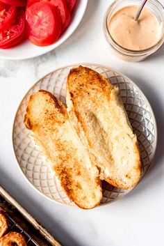 two pieces of toasted bread on a plate next to tomatoes and other food items