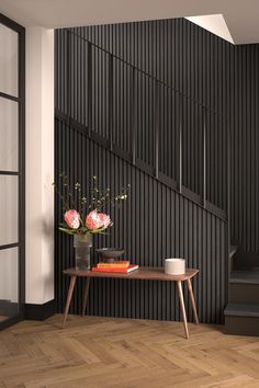 a vase with flowers on a table in front of a stair case and wooden floor