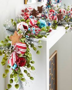 a decorated mantle with christmas ornaments and greenery on it in front of a mirror