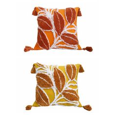 two orange and white pillows with pom poms on the bottom, one in brown and