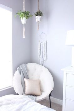 a bedroom with two hanging plants on the wall and a white chair in front of it