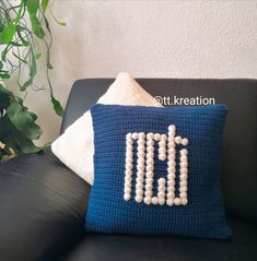 a crocheted pillow sitting on top of a black couch