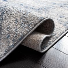 an area rug is laying on the floor next to a wooden floor with a gray and blue carpet