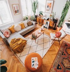 a living room filled with lots of furniture and plants on top of the wooden floor