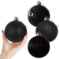 a hand holding three black and silver ornaments