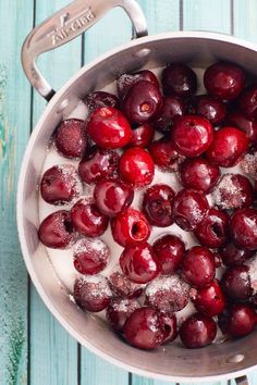 a pot filled with ice covered cherries on top of a wooden table