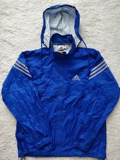 Blue Hooded Windbreaker For Streetwear, Adidas Nylon Windbreaker For Sports, Blue Hooded Track Jacket For Streetwear, Blue Hooded Jacket For Streetwear With Double-lined Hood, Blue Hooded Jacket With Double-lined Hood For Streetwear, Adidas Hooded Windbreaker With Pockets, Blue Track Jacket With Adjustable Hood For Outdoor, Blue Outdoor Track Jacket With Adjustable Hood, Sporty Blue Windproof Hooded Jacket