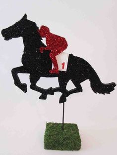 a black horse and rider on top of a green grass covered field with red glitter